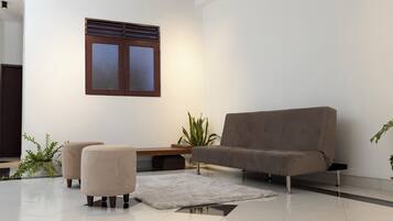 A modern living room with a sofa, ottomans, a small table, and a potted plant.