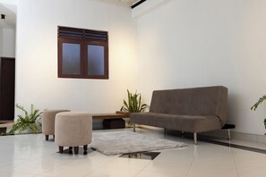 A modern living room with a sofa, ottomans, a small table, and a potted plant.