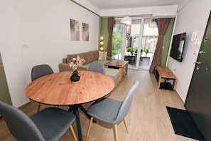 A modern living room with a round wooden table, grey chairs, a sofa, and a TV. - Lujza 1-BDR cozy APT, free parking, near the lake (Ohrid)