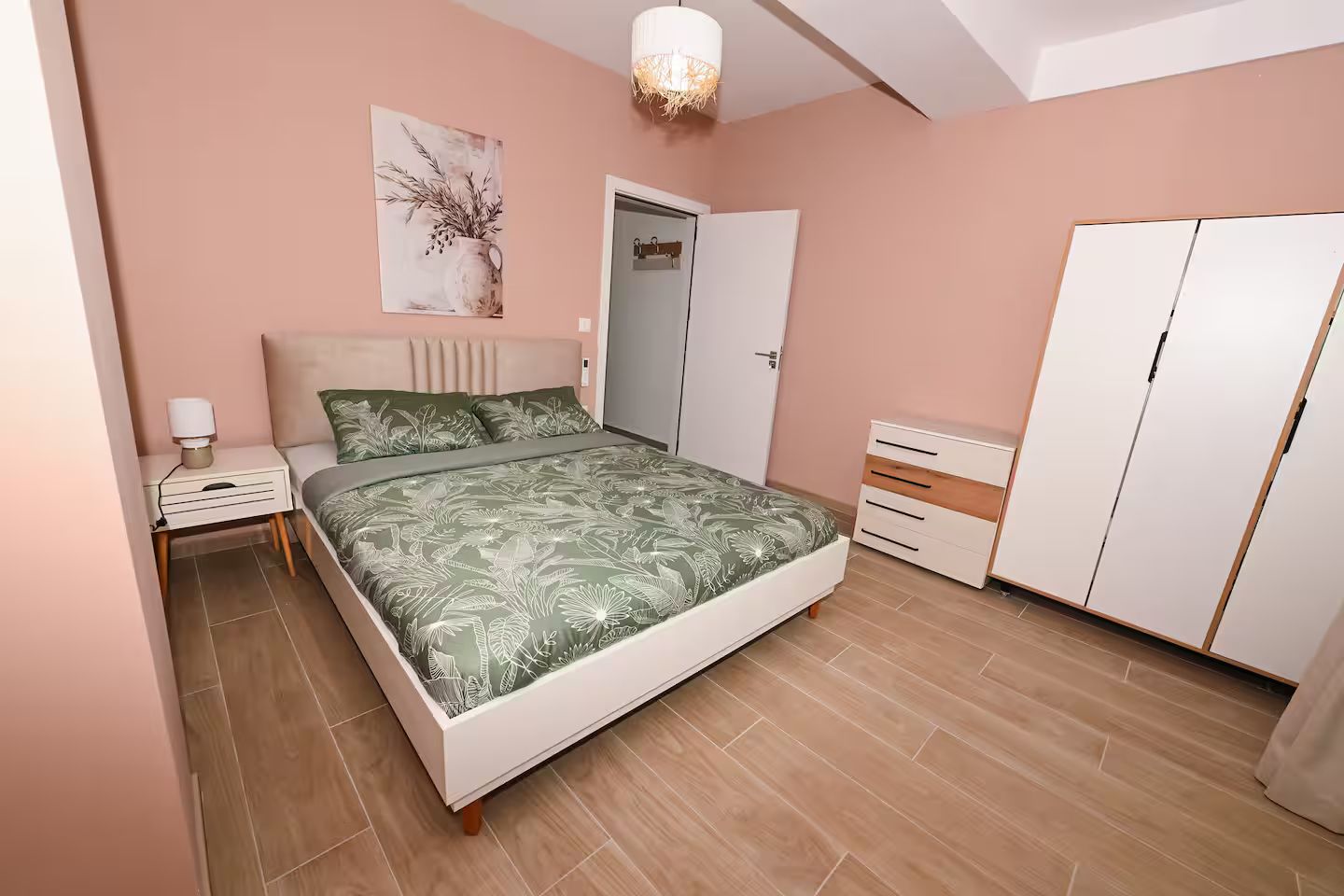 Een slaapkamer met een bed, nachtkastje, kledingkast en een deur.