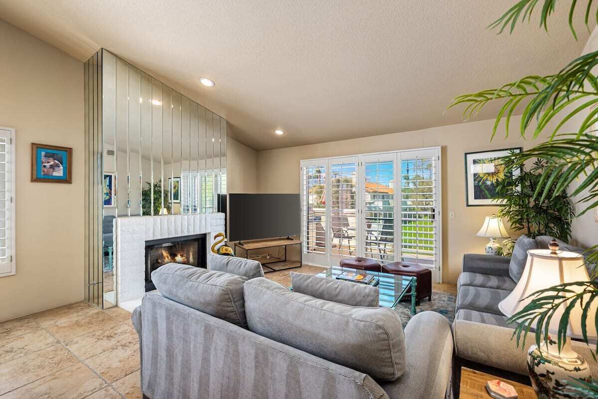 A living room with a fireplace, sofas, a TV, and a balcony with a view.