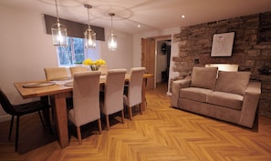 A dining area with a wooden table, chairs, and hanging pendant lights. - Peak District Country Escape - Garden, Views, Games & Fire (Combs)