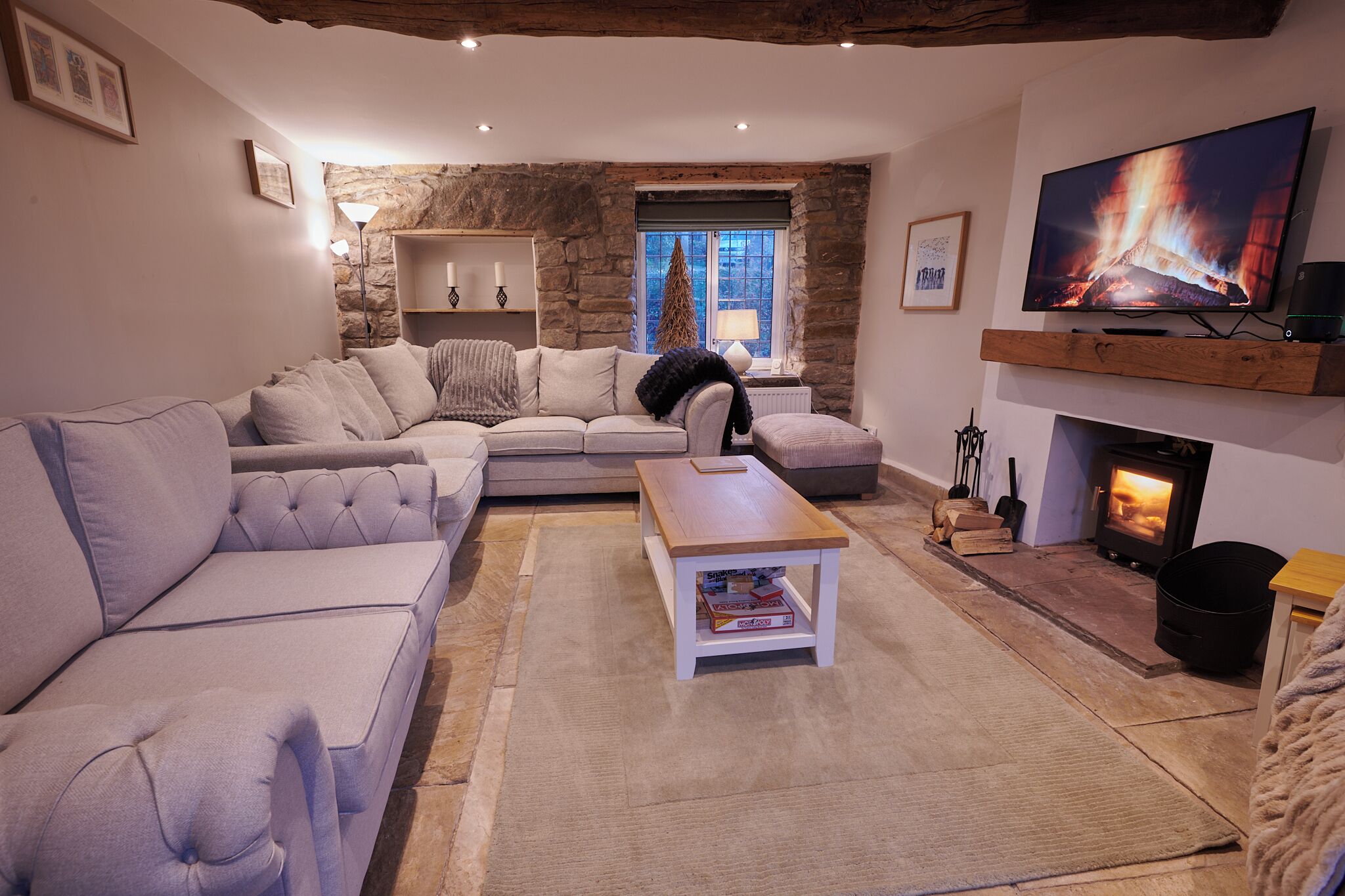 Una sala de estar acogedora con pared de piedra, chimenea, televisor y sofá.