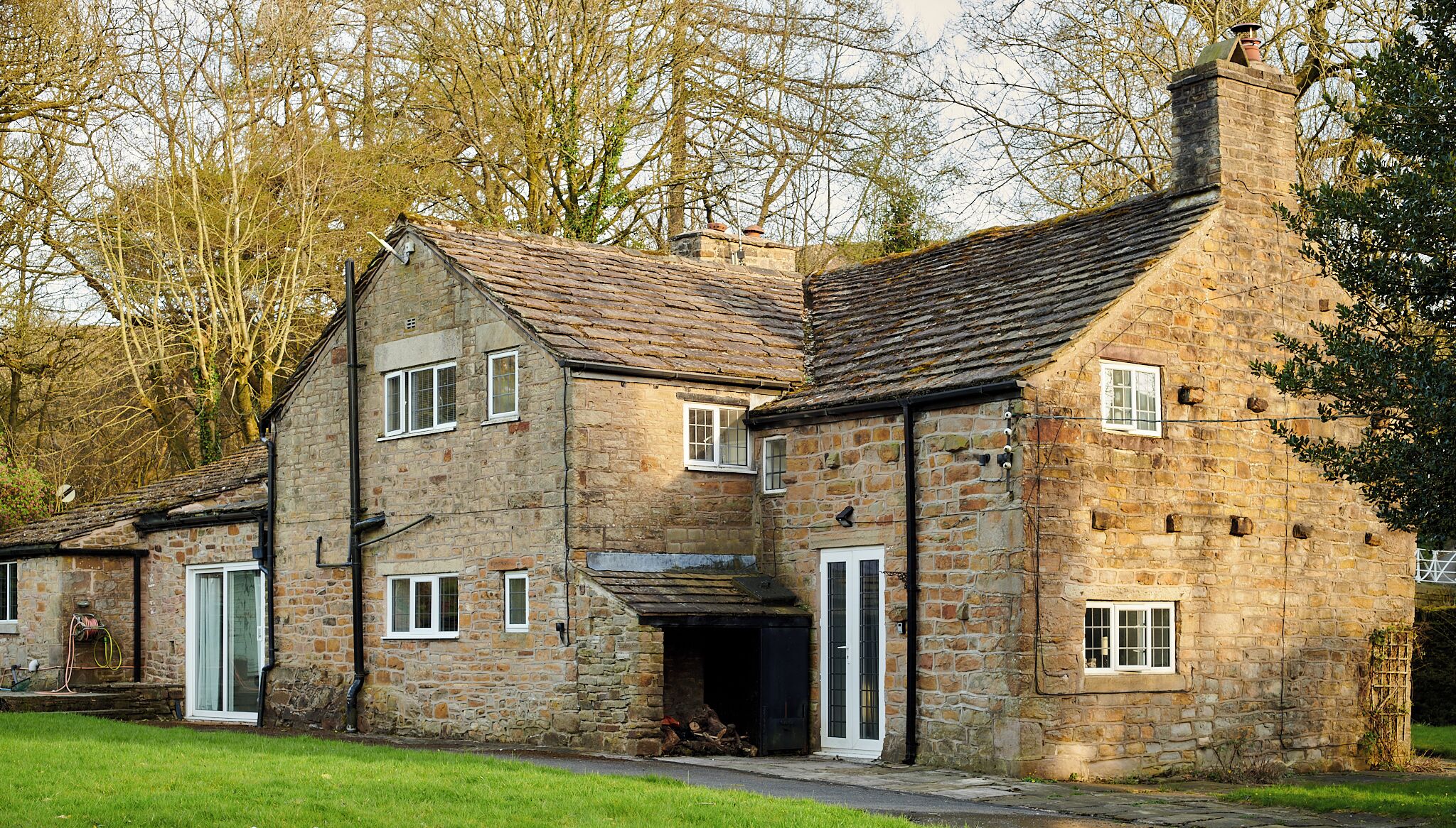 A stone building with a pitched roof, multiple windows, and a chimney.