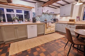 Une cuisine équipée d’un lave-vaisselle, d’une cuisinière et d’un coin repas avec des chaises.