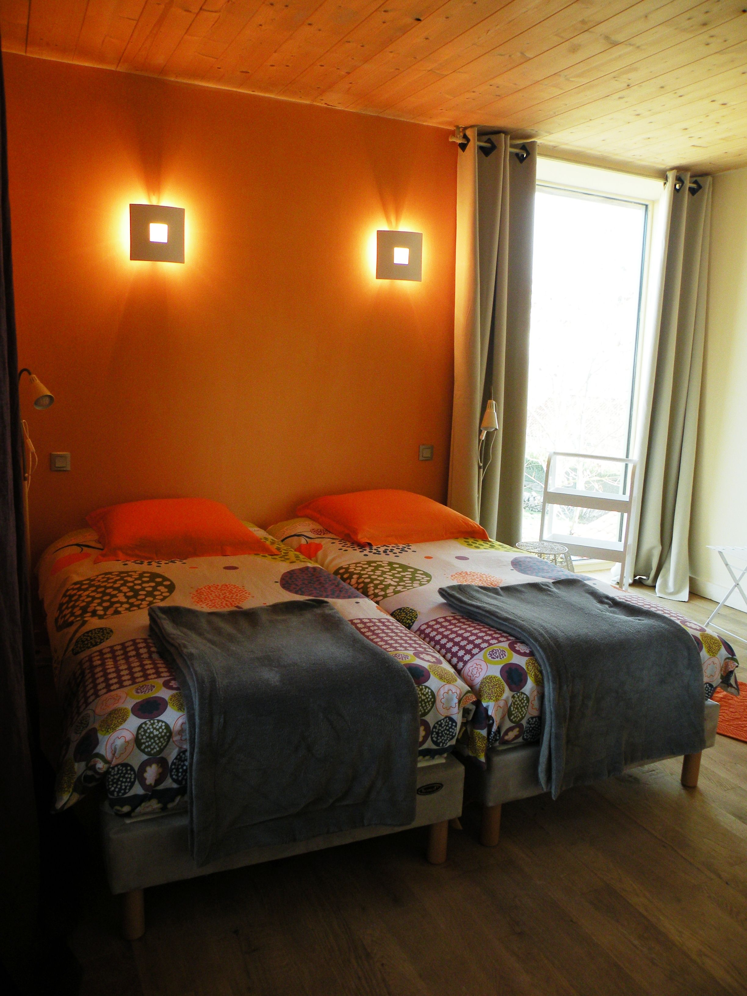 A bed with a patterned bedspread and two wall-mounted lights.
