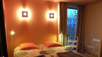 A bedroom with a bed, two bedside lamps, a chair, and a window with curtains.