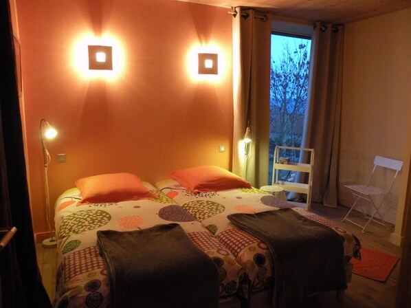 A bedroom with a bed, two bedside lamps, a chair, and a window with curtains.