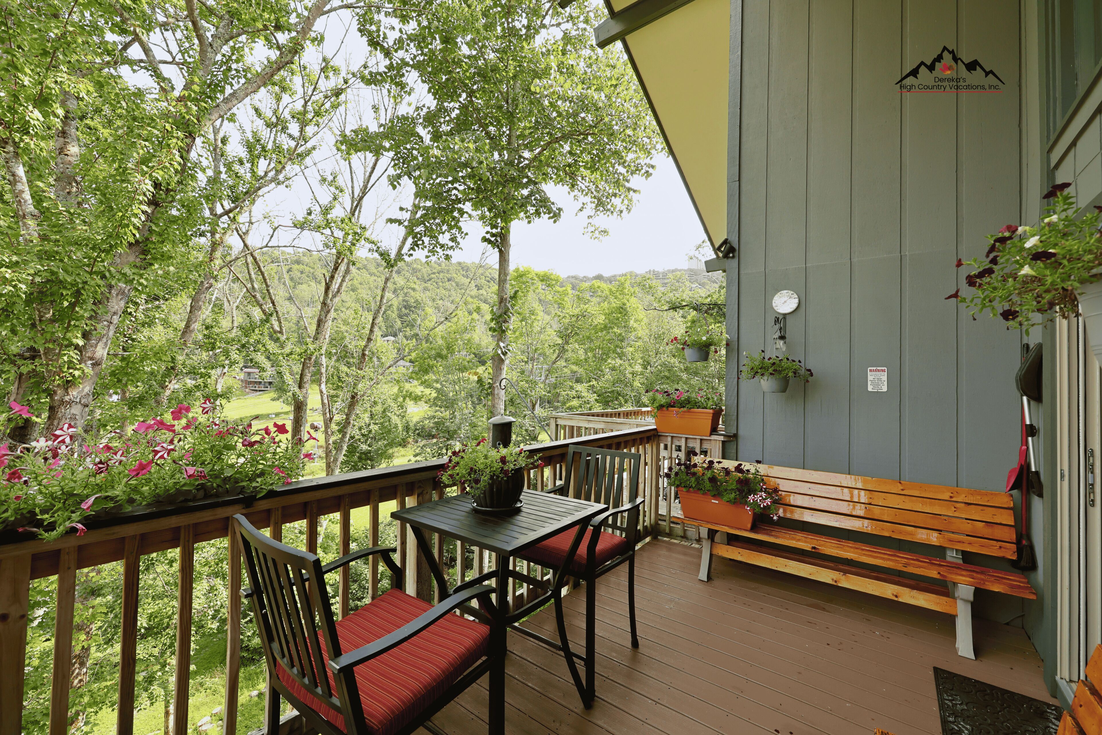 Une terrasse en bois avec une table et des chaises, entourée de verdure et offrant une vue sur une zone boisée.