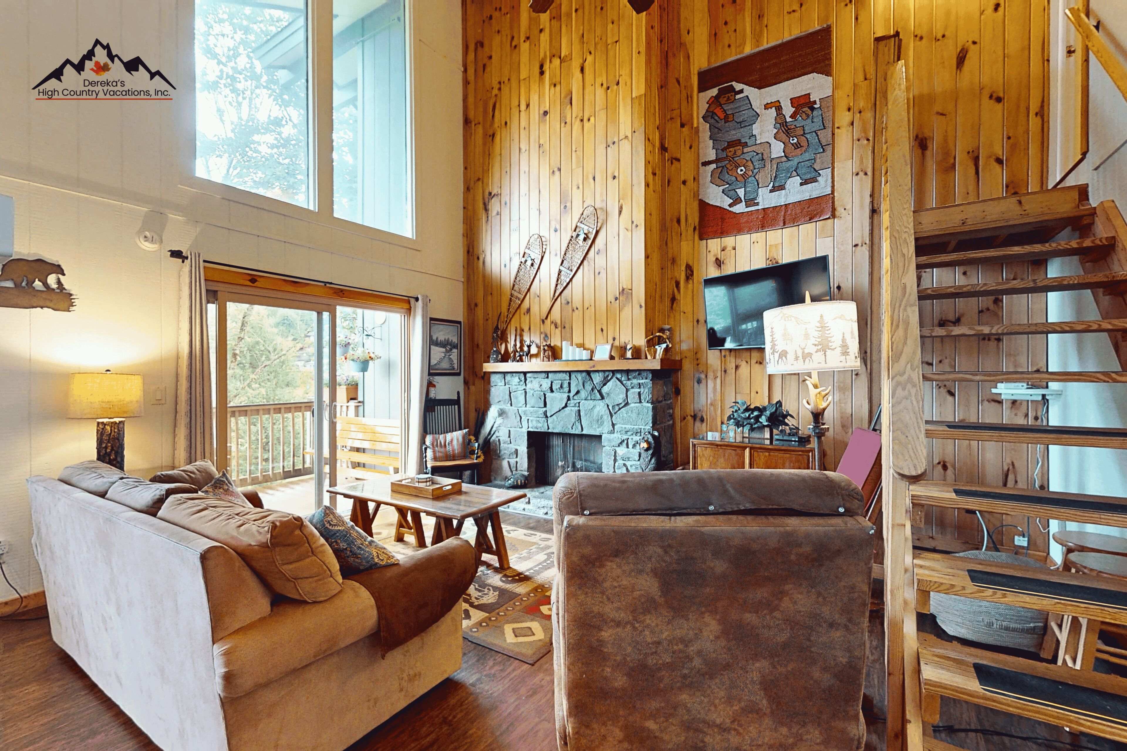 L’intérieur d’un chalet accueillant, avec une cheminée en pierre, un canapé, une table et une bibliothèque.