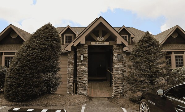A building with a stone facade, a wooden entrance, and a sign indicating the address '185 Sugar Hill.' - Top of the World Views from Sugar Mountain (Sugar Mountain)