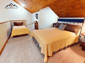 A bedroom with two beds, wooden ceiling, and a mountain logo on the wall. - Top of the World Views from Sugar Mountain (Sugar Mountain)