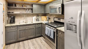Una cocina moderna con gabinetes grises, electrodomésticos de acero inoxidable, microondas integrado y estufa a gas.