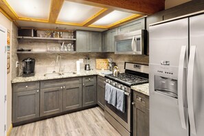 Una cocina moderna con gabinetes grises, electrodomésticos de acero inoxidable, microondas integrado y estufa a gas.