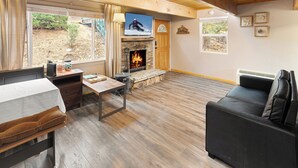 Una sala de estar acogedora con chimenea, televisor montado encima y un sofá cómodo.