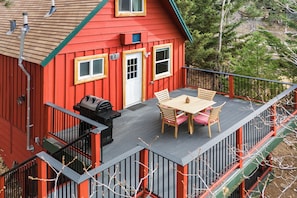 Ein rotes Gebäude mit Balkon, Grill und Tisch mit Stühlen.