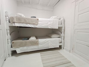 A bunk bed with white bedding and a striped rug on the floor. - A Casiña Do Río el encanto del rural. Bienvenidas mascotas. (Santa Baia Berredo A Bola)