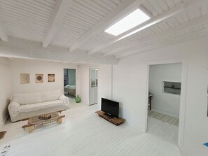 A modern living room with a white sofa, a coffee table, a flat-screen TV, and a wooden floor. - A Casiña Do Río el encanto del rural. Bienvenidas mascotas. (Santa Baia Berredo A Bola)