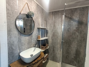 A bathroom with a round mirror, a white sink, a wooden vanity, and a glass shower enclosure. - A Casiña Do Río el encanto del rural. Bienvenidas mascotas. (Santa Baia Berredo A Bola)
