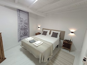 A bedroom with a bed, bedside tables, a wall-mounted light, and a decorative tapestry. - A Casiña Do Río el encanto del rural. Bienvenidas mascotas. (Santa Baia Berredo A Bola)