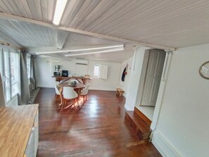 A room with a wooden floor, a dining table with chairs, a kitchen area with appliances, and a window. - A Casiña Do Río el encanto del rural. Bienvenidas mascotas. (Santa Baia Berredo A Bola)