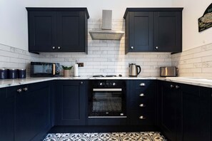 Une cuisine moderne avec des meubles de rangement de couleur sombre, un four à micro-ondes, une bouilloire et un grille-pain.