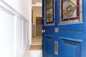 A blue door with a sign reading 'Stones Throw' and a patterned floor leading to a room with a framed picture on the wall. - Charming 2BR Flat on Grange-Over-Sands High Street (Grange over Sands)