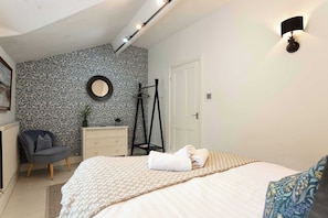 A bedroom with a bed, a chair, a dresser, and a mirror on the wall. - Charming 2BR Flat on Grange-Over-Sands High Street (Grange over Sands)