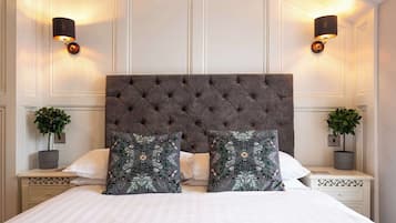 A bedroom with a tufted headboard, two bedside tables with lamps, a bed with white linens, and decorative pillows.