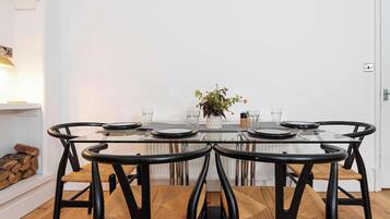 A dining area with a glass table, black chairs, and a white wall.