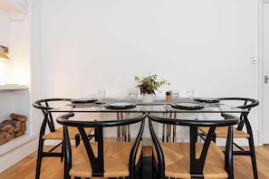 A dining area with a glass table, black chairs, and a white wall. - Charming 2BR Flat on Grange-Over-Sands High Street (Grange over Sands)