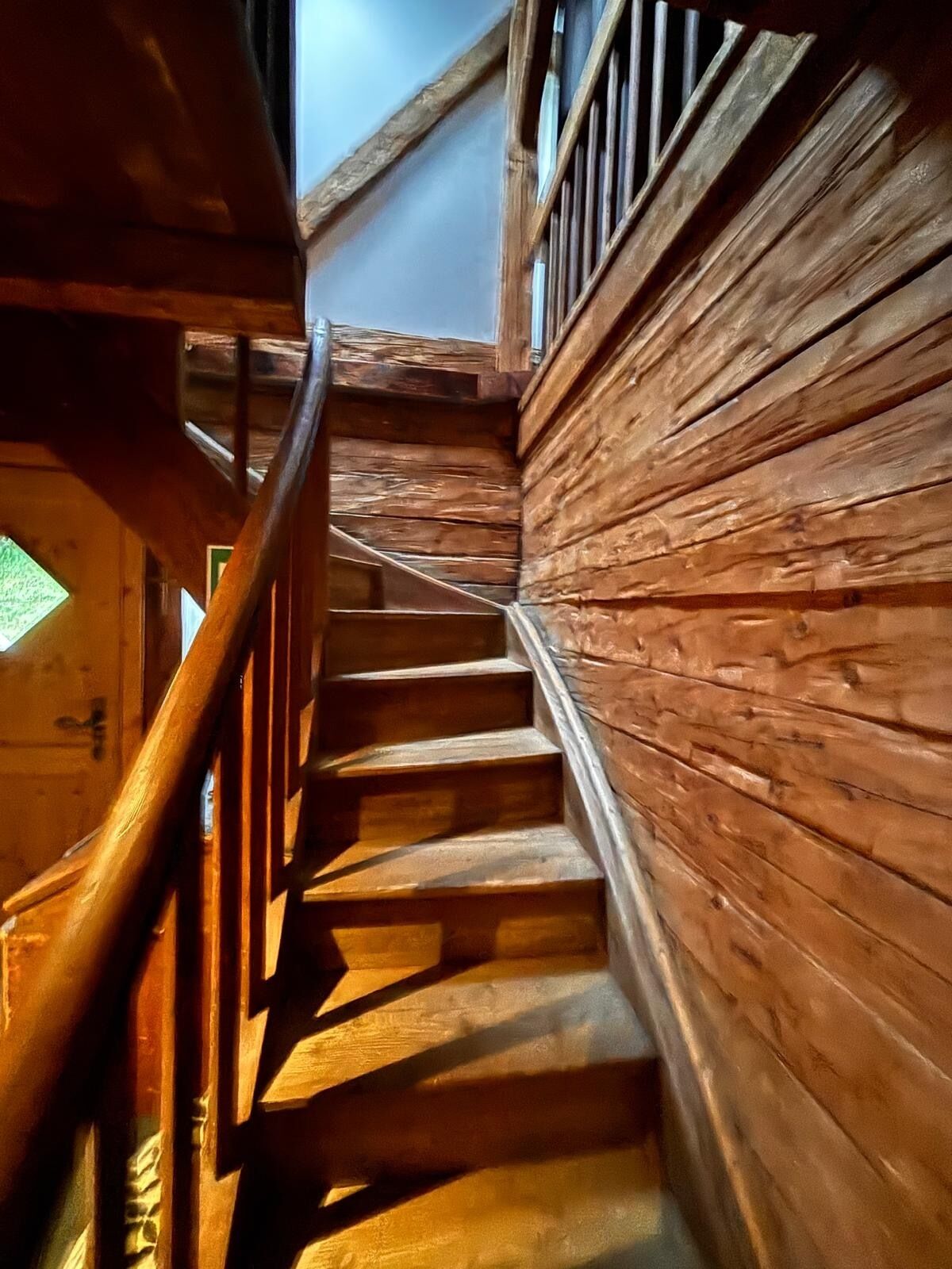 Eine Holztreppe mit Handlauf, die zu einer oberen Ebene führt.