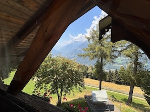 A wooden structure with a view of a mountainous landscape, a bench, and flowering plants. - Ifinger Mountain Chalet—an exclusive vacation home just for you. Modern design, quiet location. (Schenna)