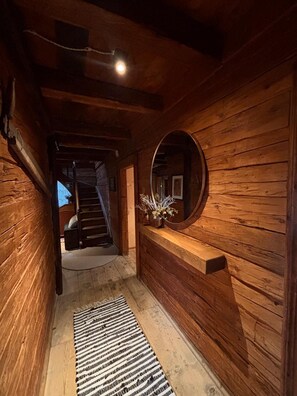 A wooden interior hallway with a mirror, a rug, and a staircase in the background. - Ifinger Mountain Chalet—an exclusive vacation home just for you. Modern design, quiet location. (Schenna)
