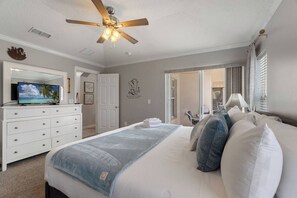 A bedroom with a bed, a television on a dresser, a ceiling fan, and a view of the outside. - Casa Sevilla | 4 BD | Sleeps 8 | Pool/Spa | Disney (Davenport)