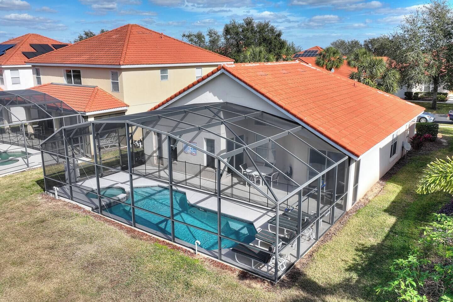 Une propriété résidentielle dotée d’une piscine, d’un patio clos et d’un toit recouvert de tuiles rouges.