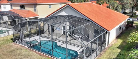 Une propriété résidentielle dotée d’une piscine, d’un patio clos et d’un toit recouvert de tuiles rouges.