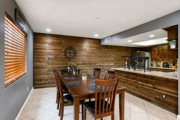 Un coin repas avec un mur en bois, une horloge et une cuisine dotée de meubles en bois.