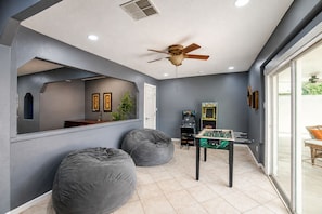A room with a foosball table, bean bags, and a ceiling fan.