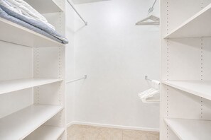 A white closet with multiple shelves and hanging space, featuring a clean and organized layout.