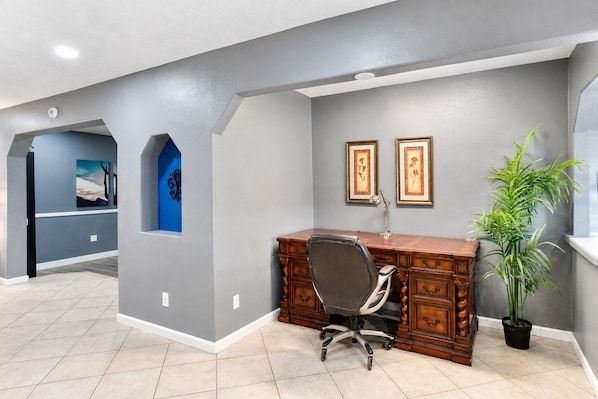 A home office with a desk, chair, and two framed pictures on the wall.