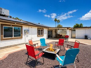 An outdoor patio with a fire pit, red and blue chairs, and a covered area with tables and chairs. - Grand Phoenix Oasis - Private Yard - Near Airport (Phoenix)