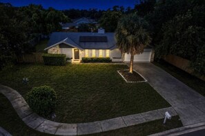 A residential house with a well-maintained lawn, a driveway, and a palm tree. - Palm Harbor Pool 4BR | Hot Tub + BBQ + Game Room (Palm Harbor)