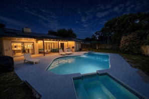 Un jardin avec une piscine, un espace salon extérieur et une terrasse couverte.