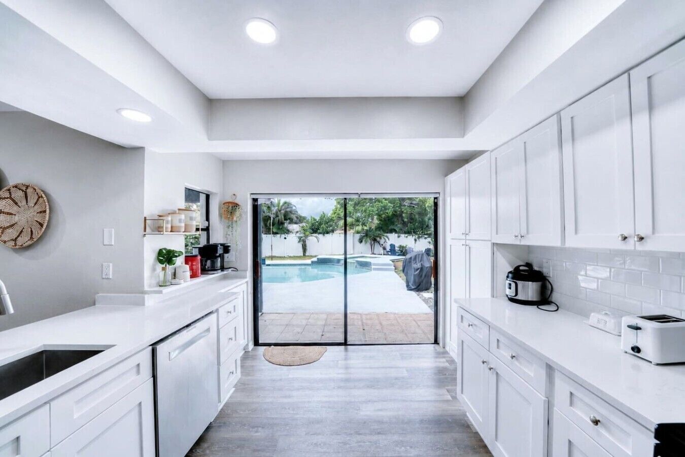 A modern kitchen with white cabinets, a built-in oven, and a view of a swimming pool.