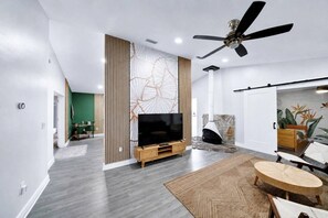 Un salon moderne doté d’un téléviseur à écran plat, d’un ventilateur de plafond et d’une cheminée.