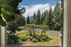 A view through a window of a landscape with trees, a road, and mountains in the background. - Sun Valley Sanctuary in Highly Sought After Location (Sun Valley)