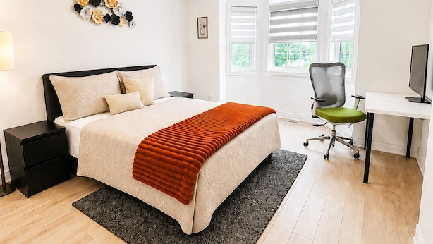 A bedroom with a bed, bedside table, desk, chair, and a window. - The Khan Villa (Whitby)