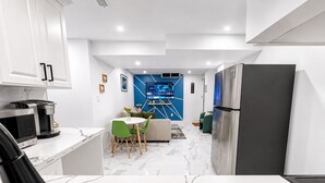 A modern kitchen with a built-in refrigerator, a coffee maker, and a dining area with a table and chairs. - The Khan Villa (Whitby)