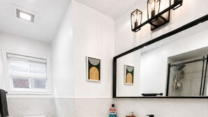 A bathroom with a toilet, sink, cabinet, and a shower area. - The Khan Villa (Whitby)